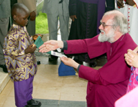 A young Anglican recieves the Archbishop with a gift of welcome at the Presidential Lodge